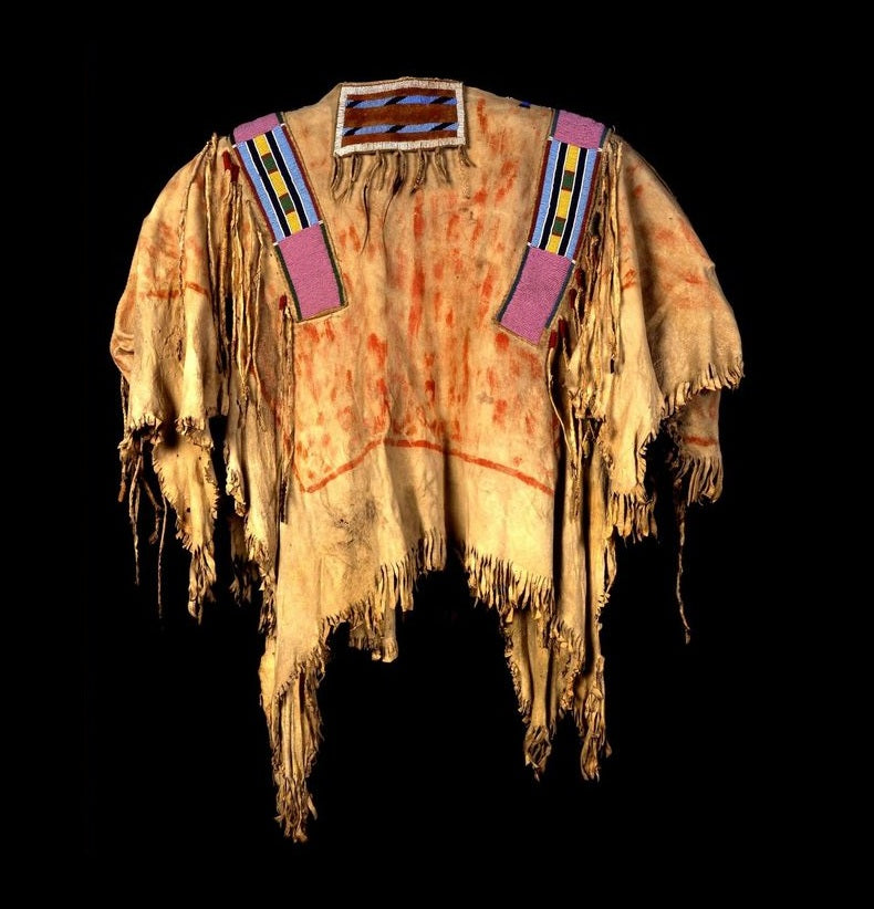 Traditional Native American garment with fringes and colorful accents on a black background