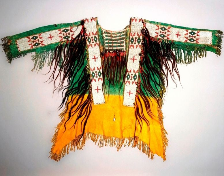 Colorful traditional garment with intricate patterns and fringes on a white background