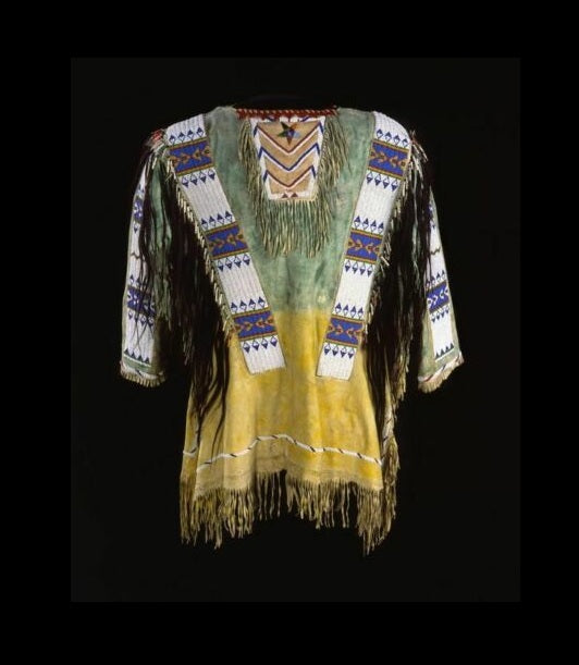 Traditional Native American garment with intricate patterns and fringes on a black background