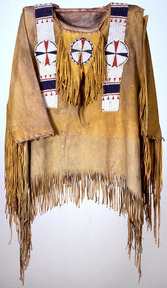 Traditional Native American garment with fringes and beadwork on a plain background