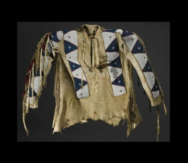 Traditional Native American garment with intricate patterns and fringes on a dark background